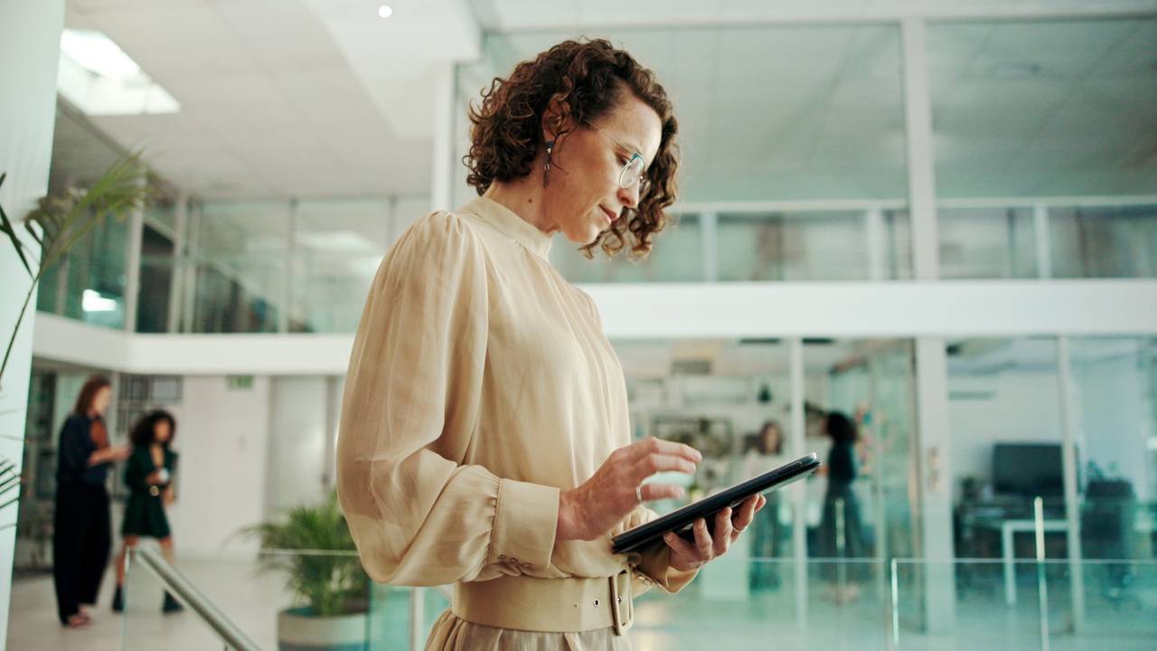 HR professional reviewing workforce compliance data on a tablet in a modern office environment.