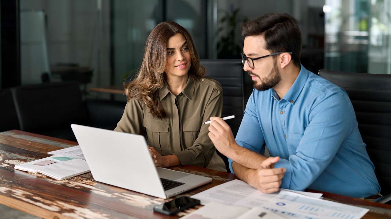 Two professionals reviewing visa application documents and test score requirements on a laptop, symbolising guidance on Australia’s updated English language rules.